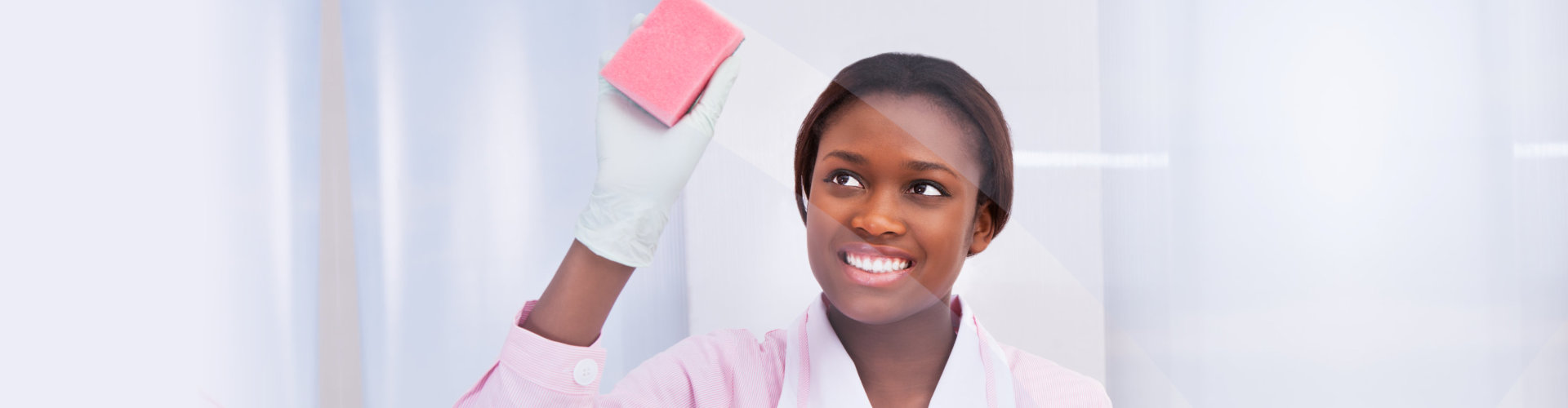 woman in pink smiling while cleaning the glass